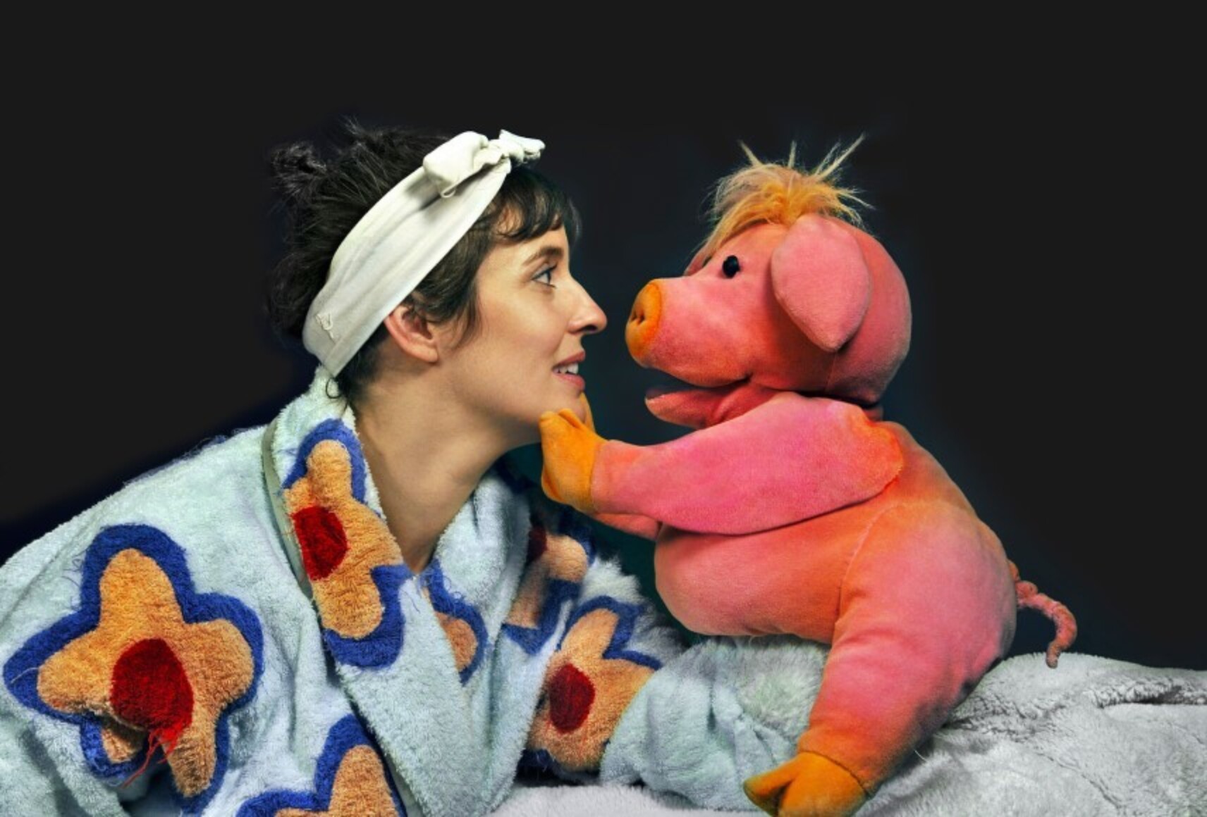Madame Pin Pon, en peignoir bleu avec de grosses fleurs orange et rouge, fait face au petit cochon. Ils se regardent dans les yeux, le cochon posant une patte sur le menton de Madame Pin Pon.