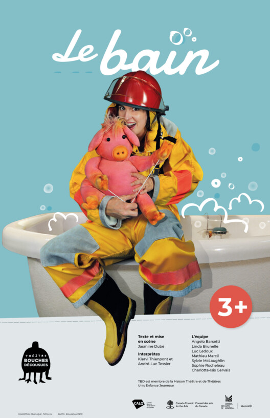 Affiche du spectacle "Le Bain". Un personnage est assis au bord d'un bain et tient une marionnette cochon dans ses bras. Elle porte une combinaison de pompier jaune, rose et bleue et un casque de pompier rouge. Sa botte noire et jaune dépasse de la photo.