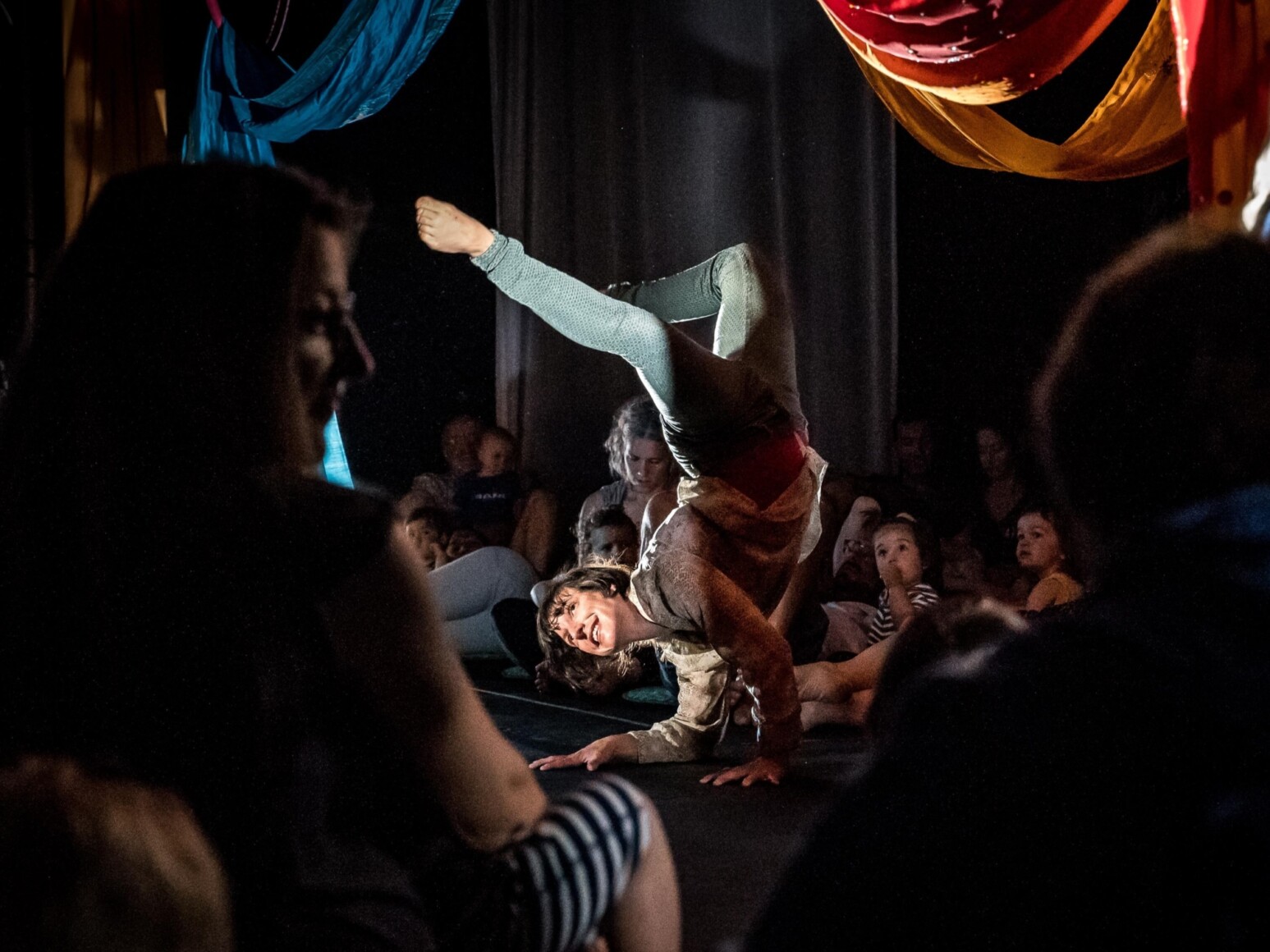L’artiste Nadine Louis en position de contorsion au sol parmi les spectateurs