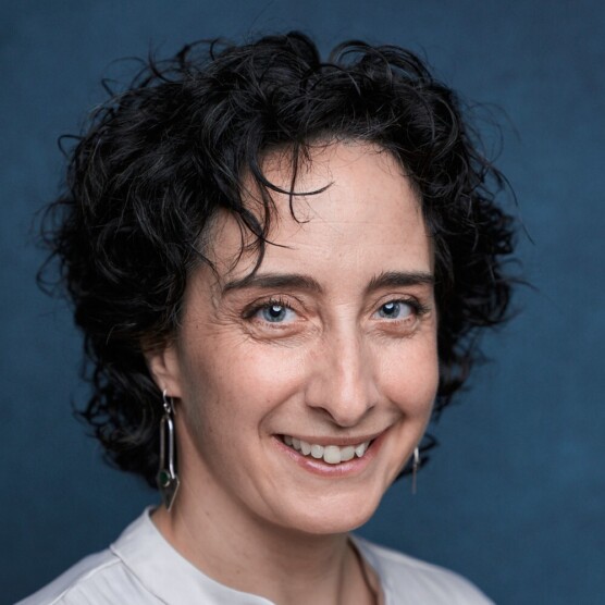 Photo portrait de l’artiste Laurence Racine, caucasienne, yeux bleus perçants, cheveux bruns frisés