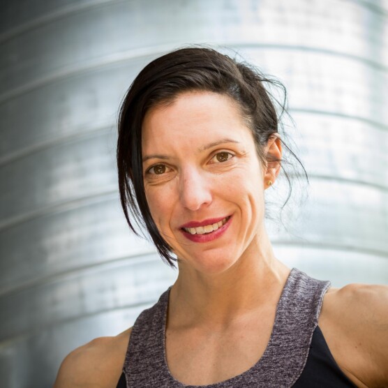 Photo portrait de l’artiste Nadine Louis, caucasienne, yeux et cheveux bruns, sourire timide
