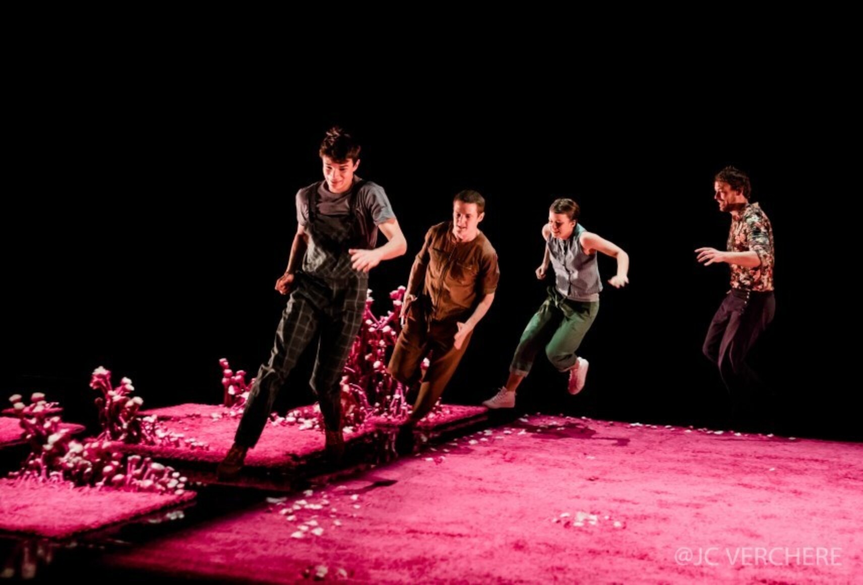Quatre personnages courent devant un fond noir sur le tapis rose fuchsia d'où émergent des sortes de champignons roses. Ils portent des vêtements de couleurs et motifs variés.