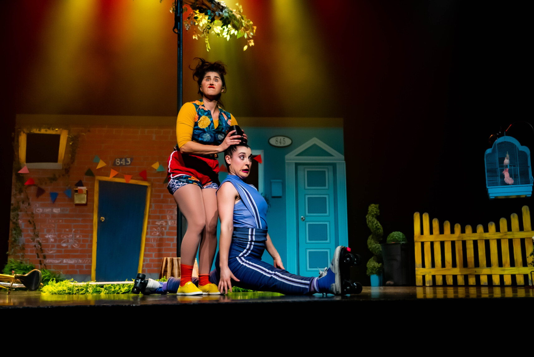 Une artiste de cirque en patin à roulettes fait le grand écart. L'autre artiste clown lui tient le chignon.