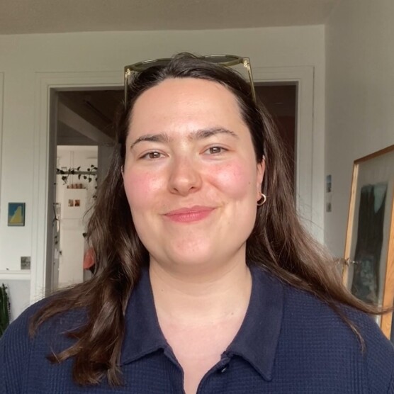 Portrait souriant d’une personne aux cheveux longs, dans un intérieur lumineux.
