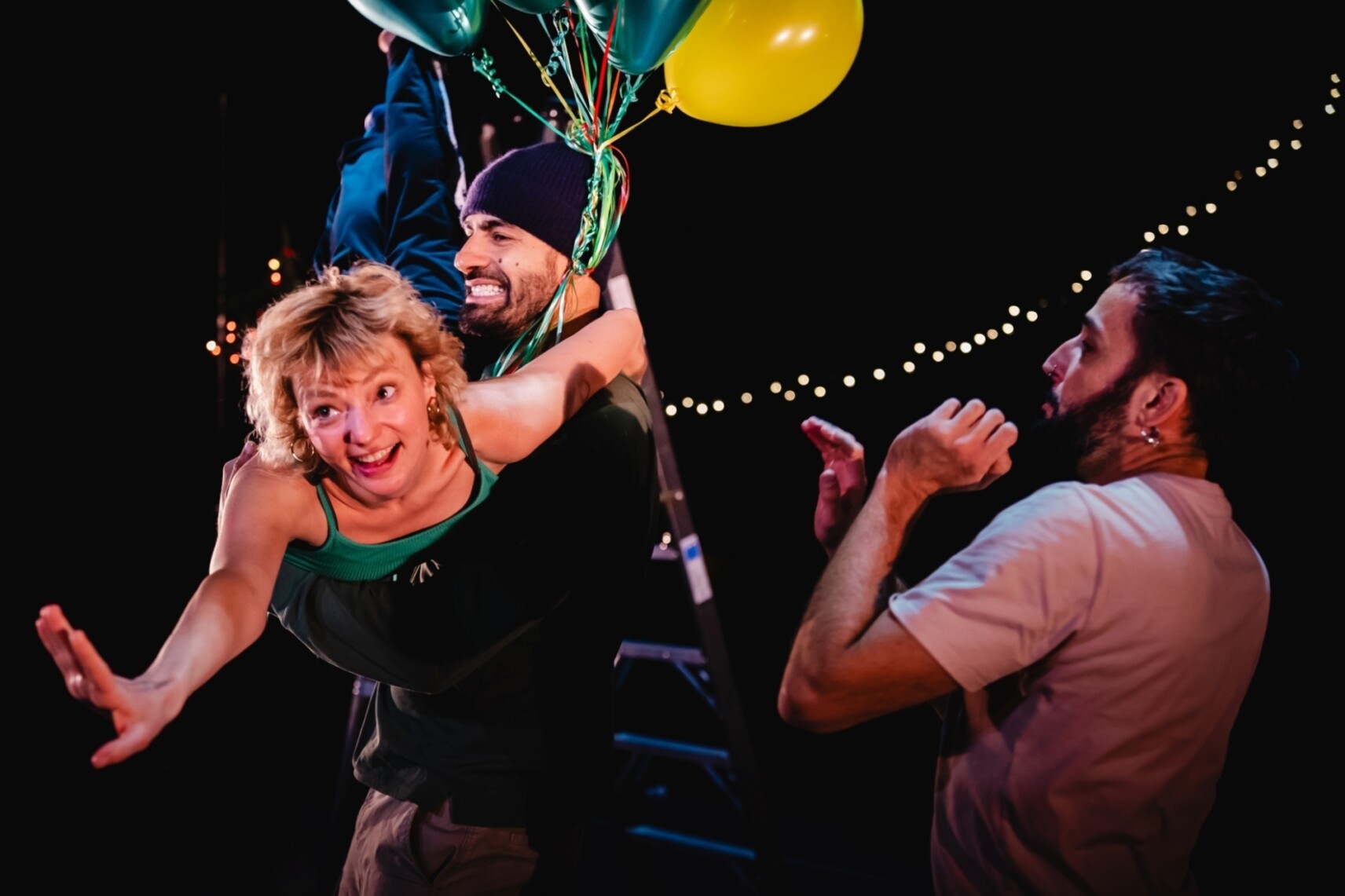 Photo d'un grand personnage masculin qui porte dans ses bras un petit personnage féminin et un bouquet de ballons. Les deux semblent rire et s'amuser. Un troisième personnage masculin est derrière eux, comme surpris de la scène.