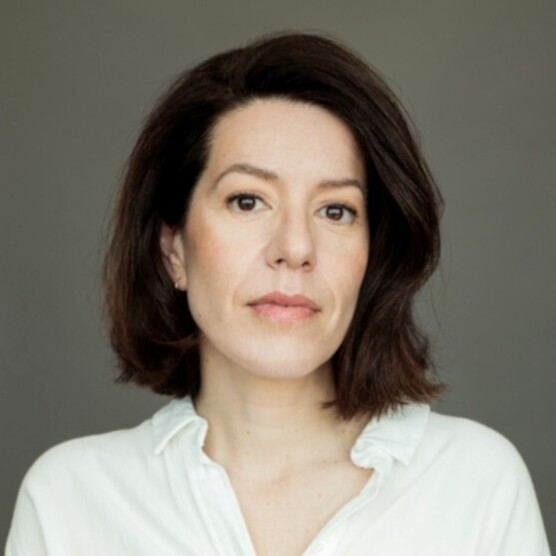 Photo d'une femme, yeux bruns et cheveux bruns mi-longs en chemise blanche.