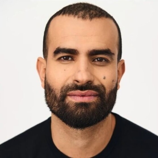 Photo d'un jeune homme au teint basané, les yeux et les cheveux foncés, rasés de près et la barbe courte.