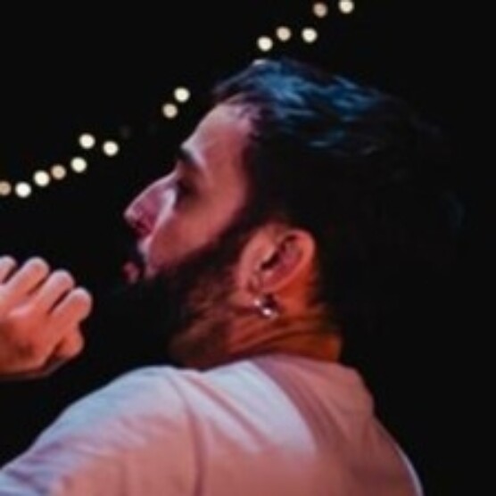 Photo d'un jeune homme barbu en train de se débattre avec des ballons colorés en souriant de toutes ses dents.