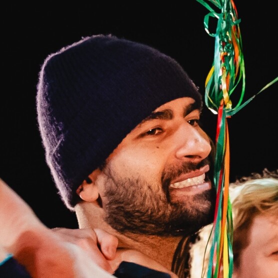 Photo du profil d'un jeune homme avec une tuque, la barbe foncée et courte, tout sourire.