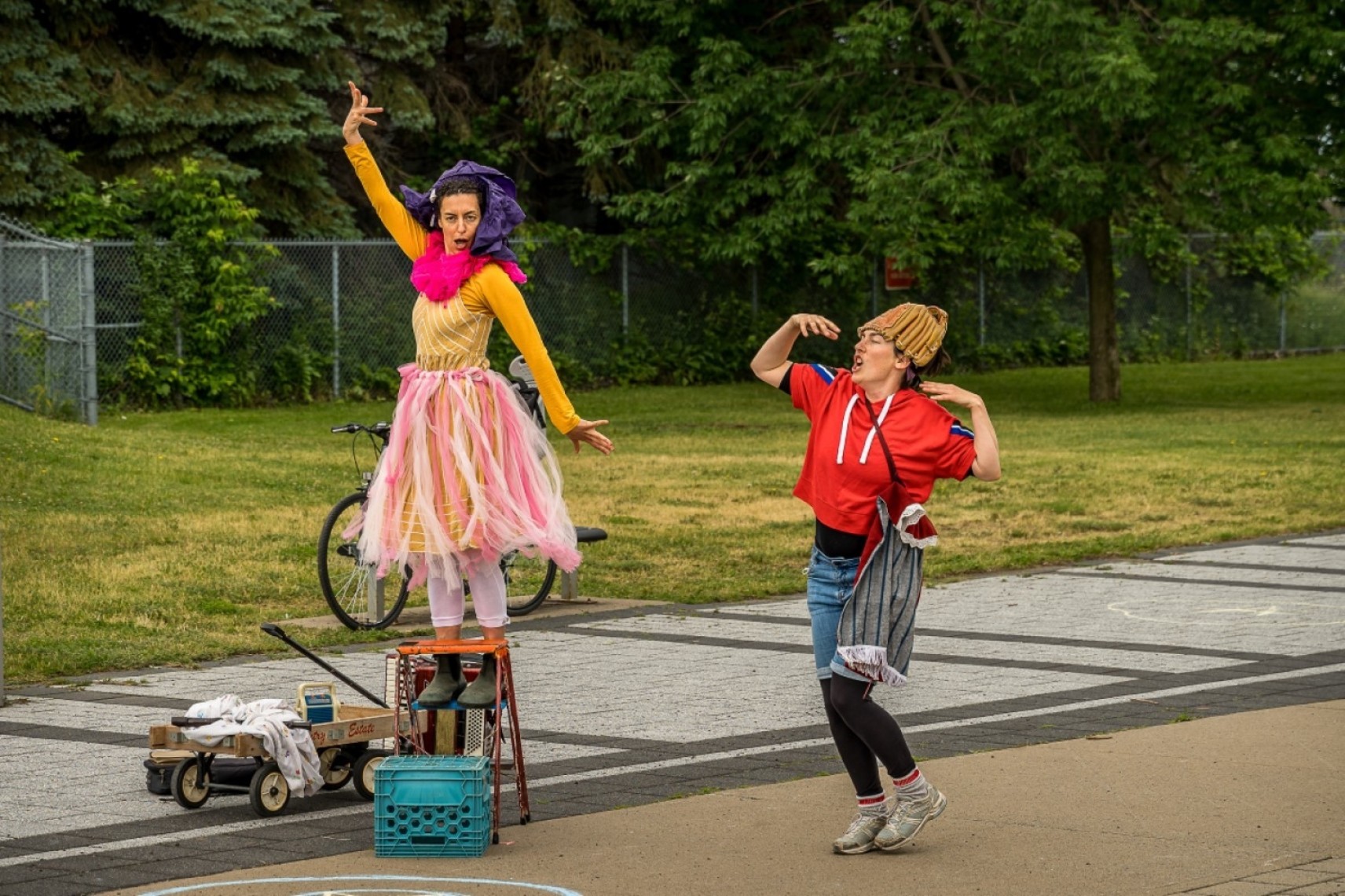 Photo en extérieur des personnages d'Amarelinha et Simone, avec divers accessoires. Elles font des poses dynamiques avec leurs bras et ont des visages expressifs.