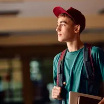 Pensive teenage boy in high school hallway looking away. Copy space.