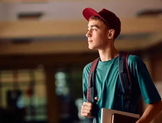 Pensive teenage boy in high school hallway looking away. Copy space.